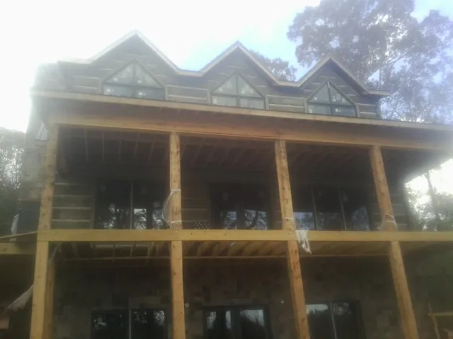 Dormers and porch framing on a large log home under construction — Roof Coating work by our crew in Campton