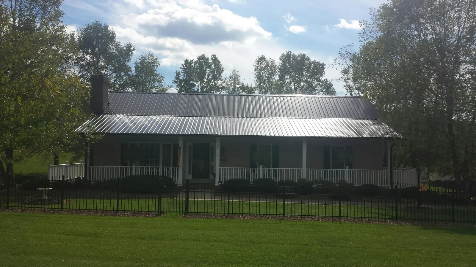 Gray metal roof on a brick ranch with a full width front porch — Gutter Guard Installation work by our crew in Campton