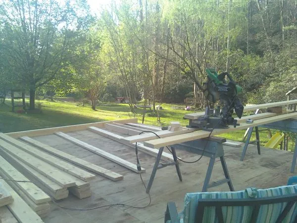 Miter saw and framing lumber on a deck under construction in Campton