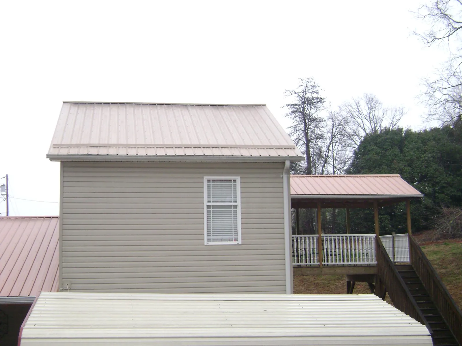 Tan metal roofs on a two story addition and attached porch, from a Roof Replacement job in Campton