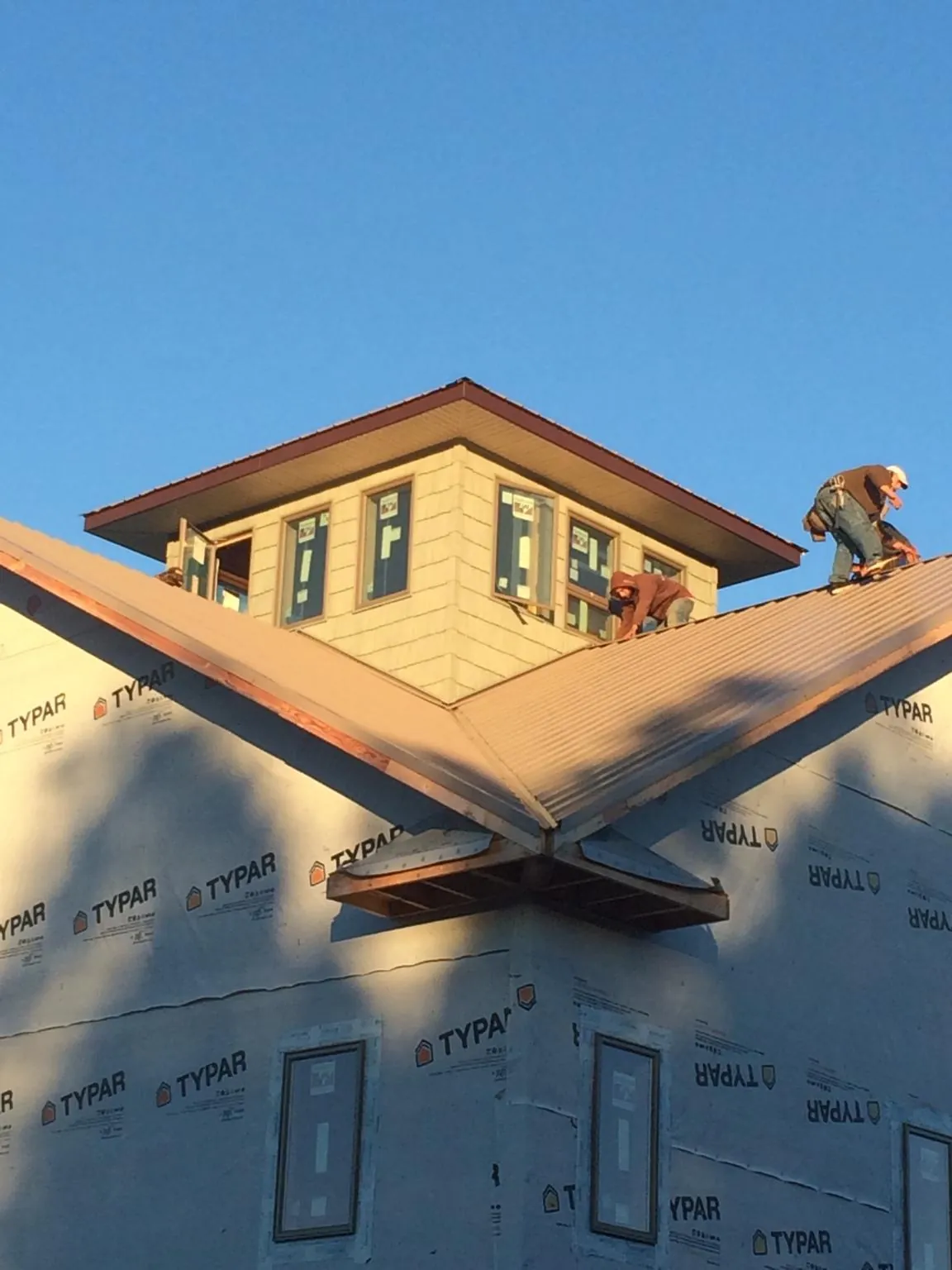 Roofers working around a rooftop cupola on a new metal roof at sunset — Roof Waterproofing in Campton by Roofing Brothers